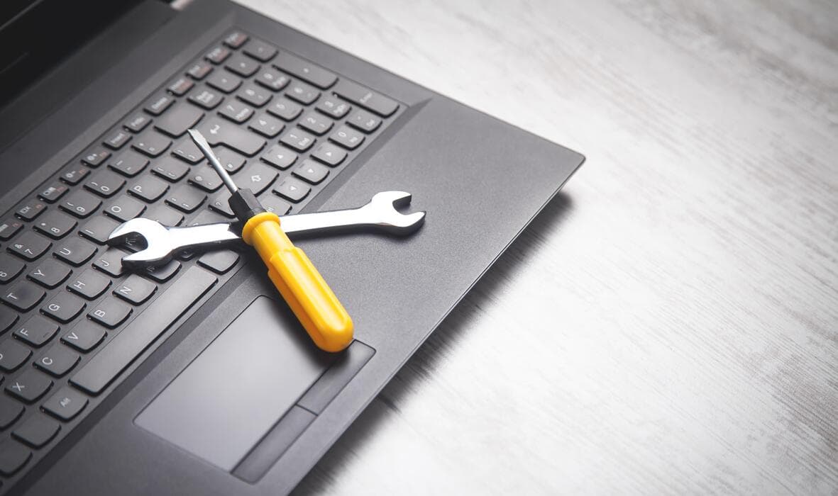 Tools on a laptop keyboard representing laptop repair service